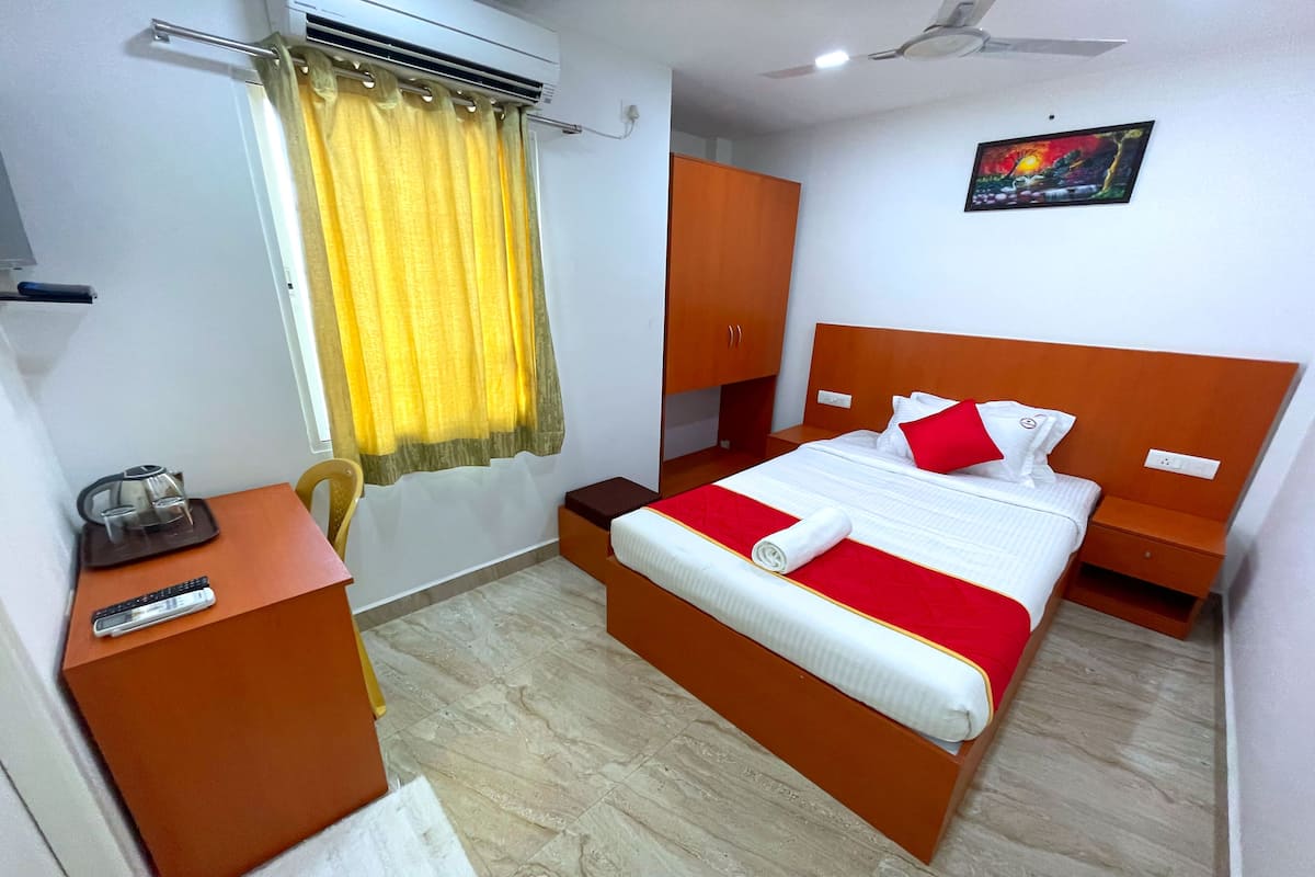 Une chambre d’hôtel avec un lit, un bureau, une chaise, une armoire et un tableau au mur.