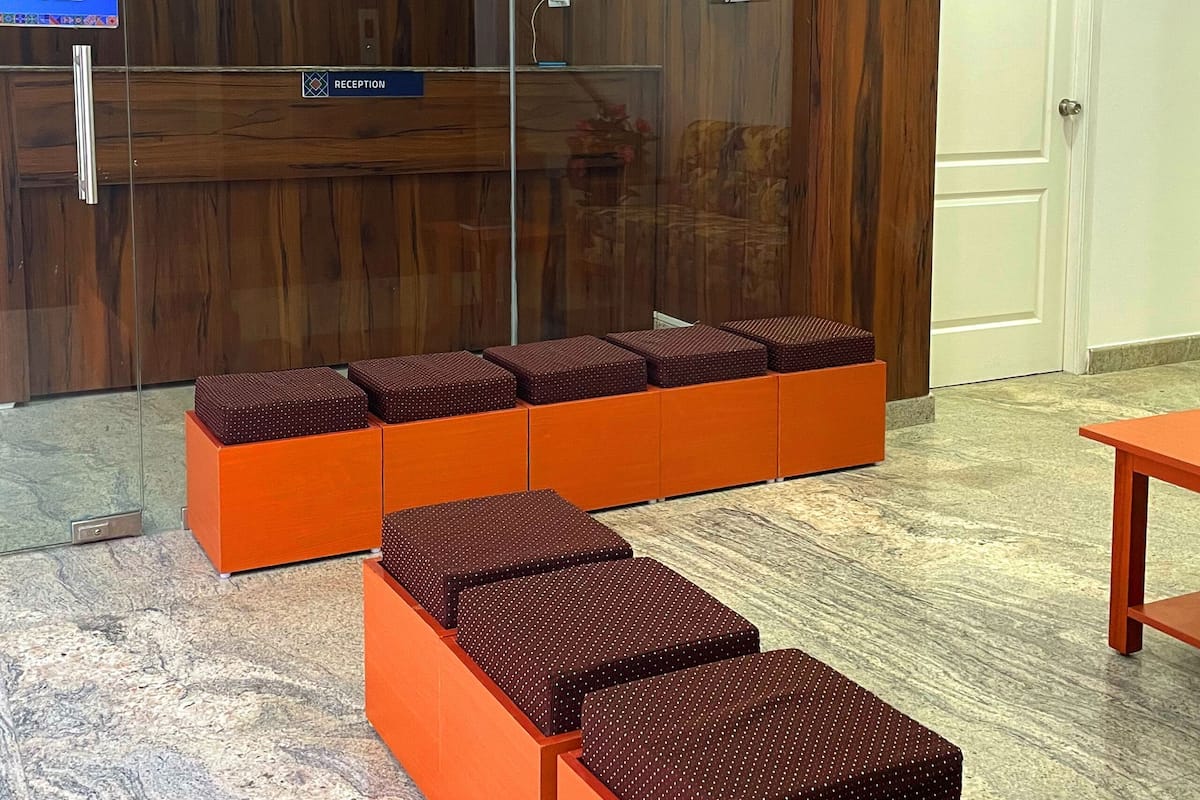 Un espace d’accueil doté d’un mur en verre, de lambris en bois et de sièges orange.