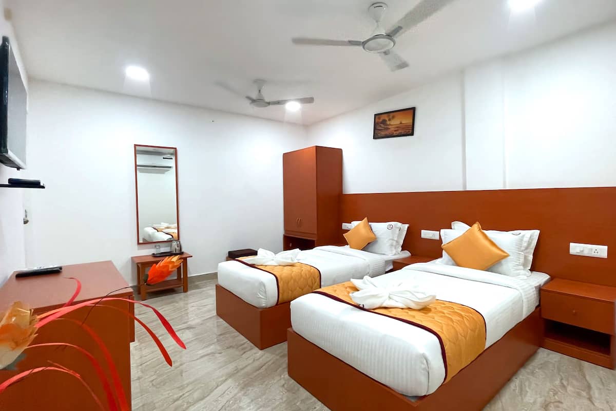 Une chambre d’hôtel avec deux lits, un bureau, un miroir et un ventilateur de plafond.