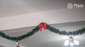 Un comedor con mesas y sillas, decorado con guirnaldas y una figura de Papá Noel.