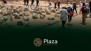 Un grupo de personas caminando por un sendero rocoso en un paisaje desértico, con una montaña al fondo.