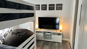Een slaapkamer met stapelbedden, een televisie, een console en inspirerende wanddecoratie.