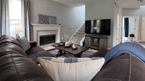 Een woonkamer met een open haard, een bank, een salontafel en een televisie.