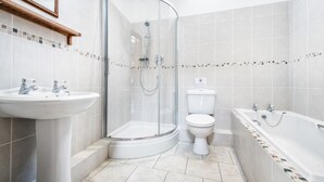 Uma casa de banho moderna com cabine de duche em vidro, lavatório branco, sanita e banheira.