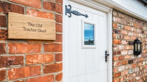 A wooden sign reading "The Old Tractor Shed" mounted on a brick wall. - The Old Tractor Shed (Driffield)