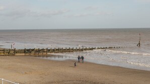 A beach with a wooden jetty and a lifebuoy. - The Old Tractor Shed (Driffield)