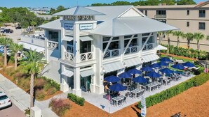 A beachfront restaurant with outdoor seating and a view of the ocean. - Beach Bliss: Beach Minutes Away, 6-Seater Golf Cart, and Sparkling Resort Pool! (Santa Rosa Beach)