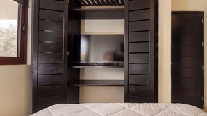 Un dormitorio con cama, repisa para televisor y armario.