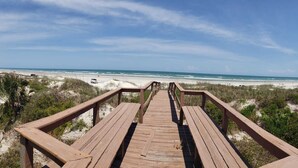 A wooden boardwalk leading to a beach with sand dunes and sparse vegetation. - Castaway Cottage - Private Beach Walkway, Beautiful Views, Ping Pong Table! (St. Augustine)