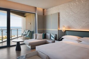 A modern hotel room with a balcony, a sofa, a bed, and a small table.