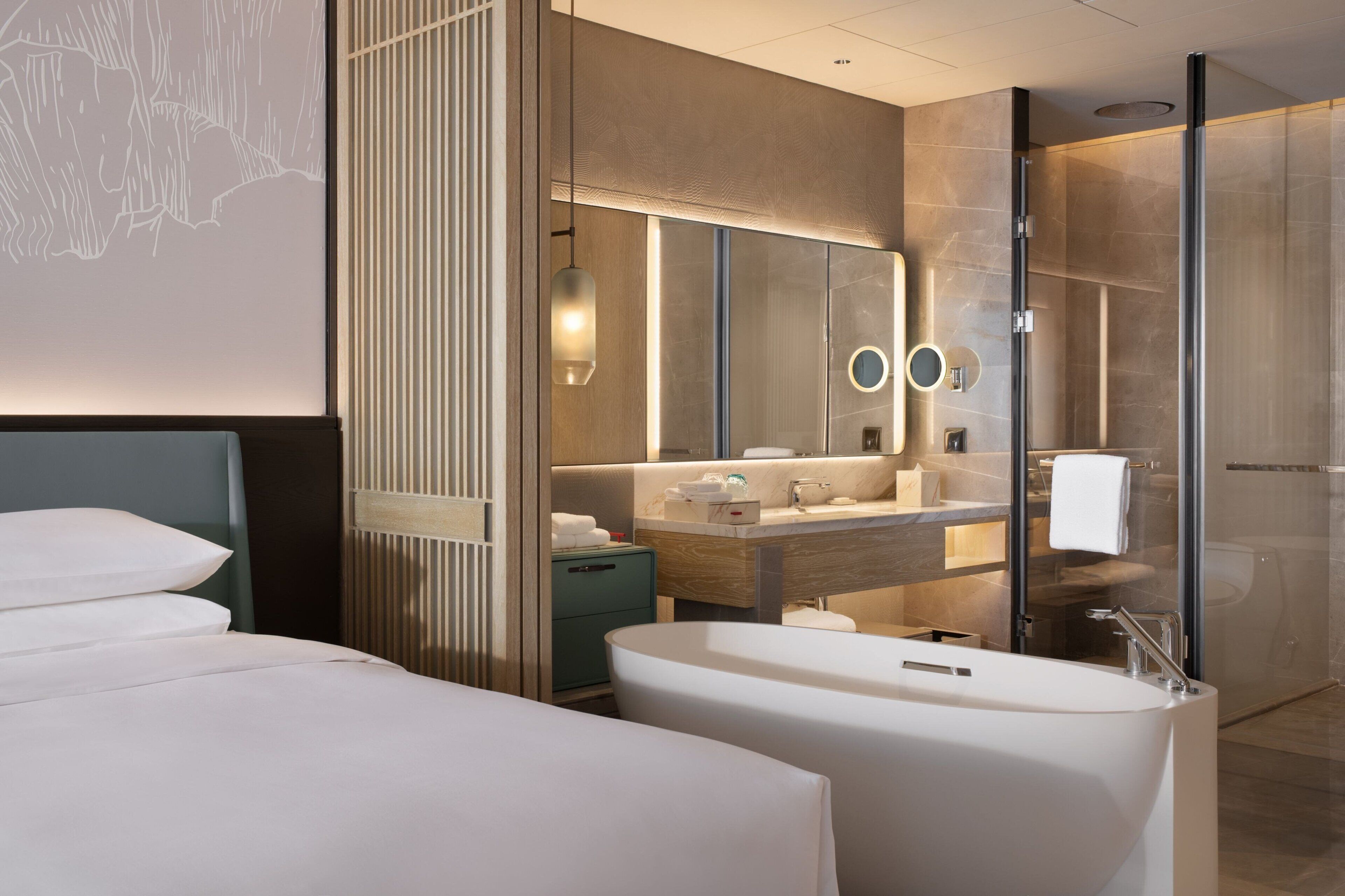 A modern hotel bathroom with a large bathtub, a vanity with a mirror, and a shower area.