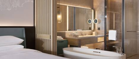 A modern hotel bathroom with a large bathtub, a vanity with a mirror, and a shower area.