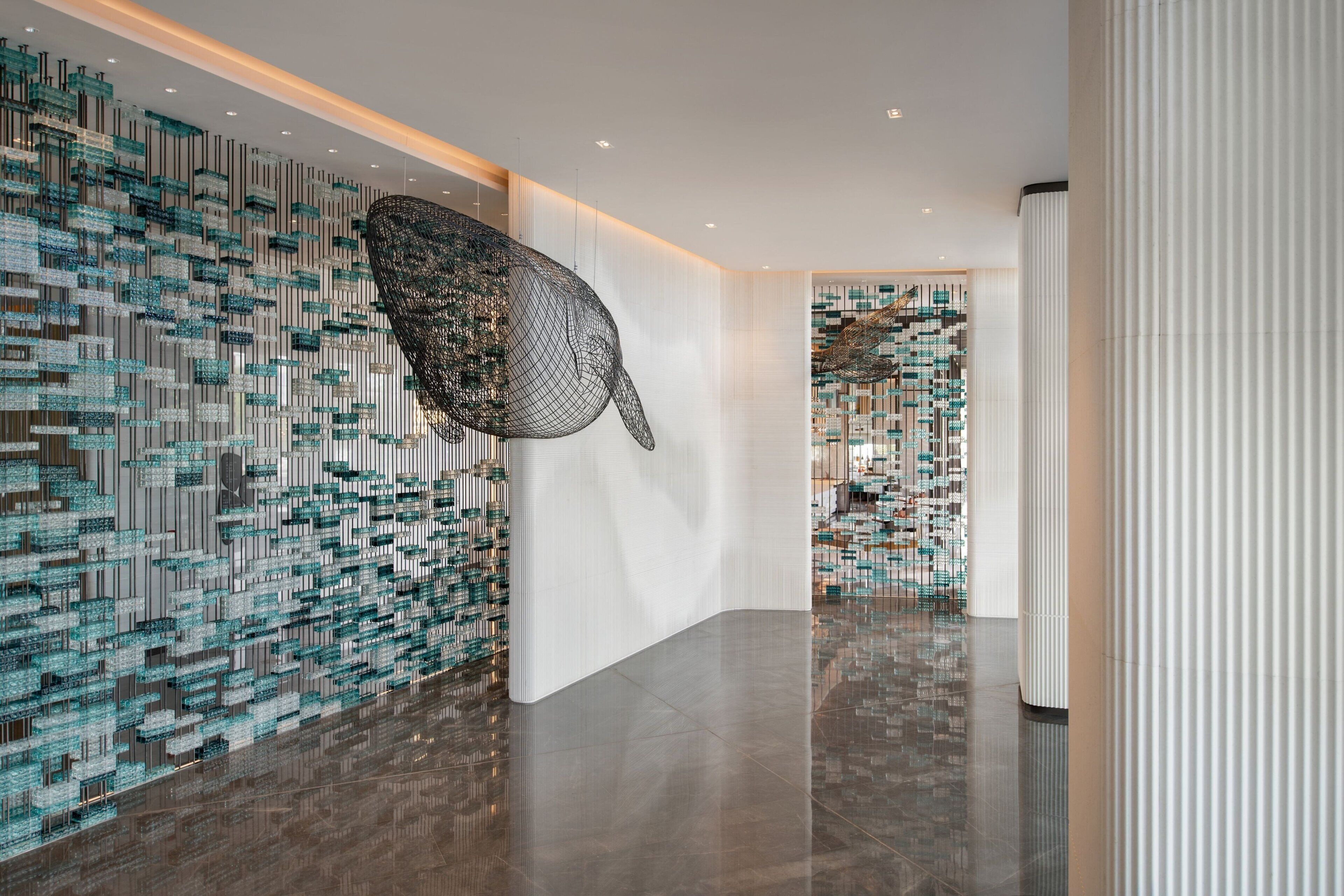 Een moderne lobby met een grote abstracte sculptuur, behang met patronen en een gepolijste vloer.