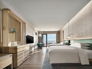 A modern hotel room with a large bed, a TV, a dining area, and a view of the city. - Qinhuangdao Marriott Resort (Qinhuangdao)