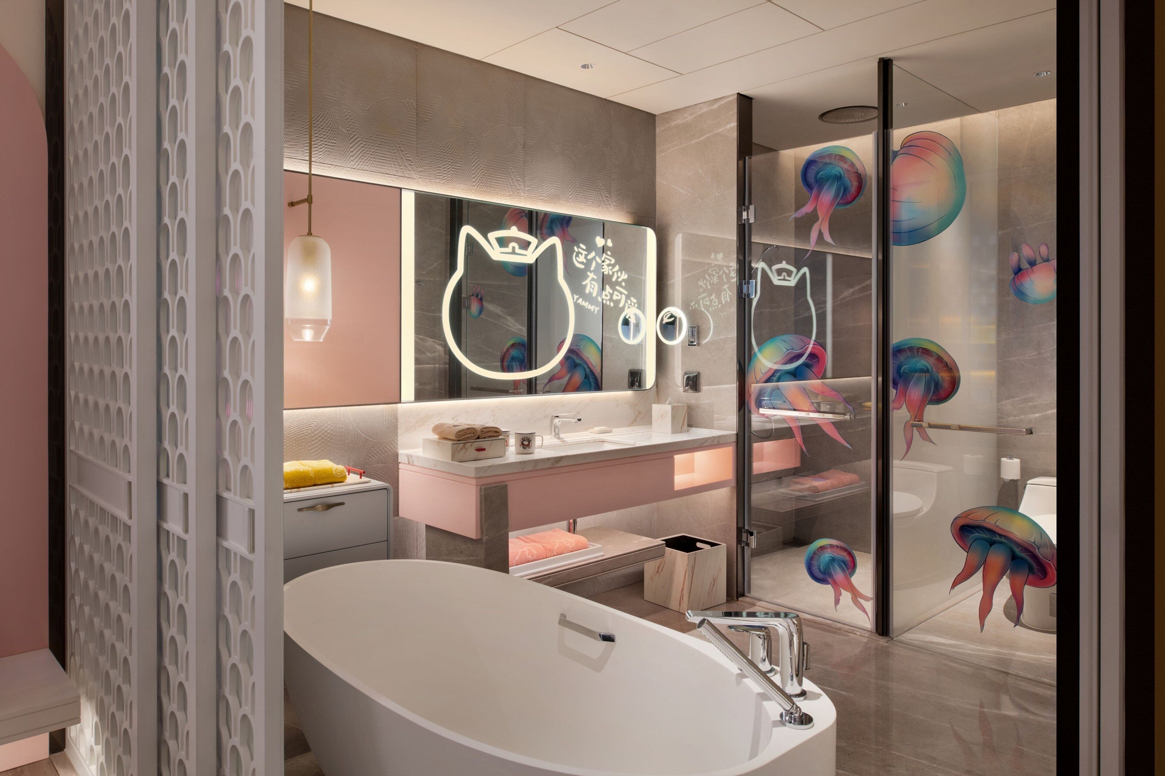Een moderne badkamer met een vrijstaand bad, een wastafel met spiegel en een douchecabine van glas met kleurrijke kunstwerken.