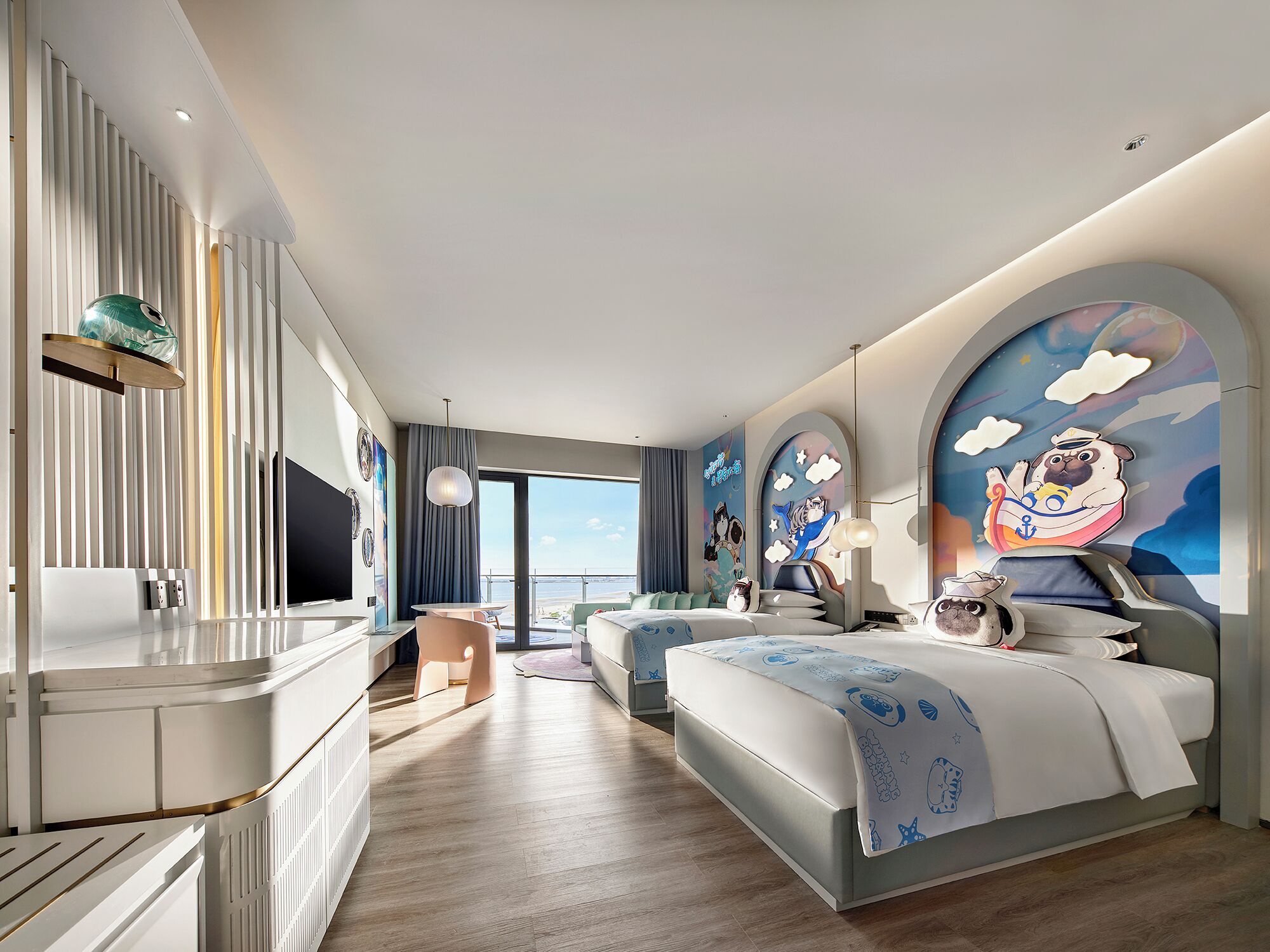 A modern hotel room with a large bed, a desk, and a view of the sea.