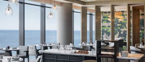 A modern dining area with large windows, a central island, and hanging pendant lights.
