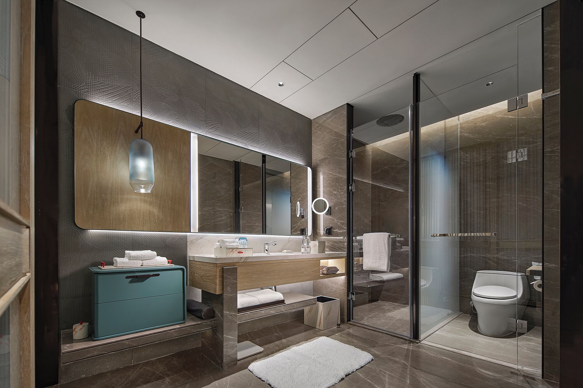 A modern bathroom with a large mirror, a vanity with a sink, a shower area, and a toilet.