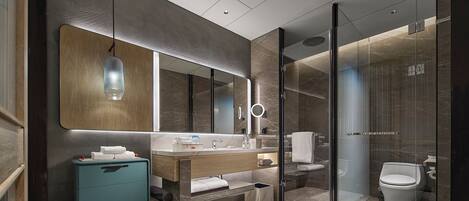 A modern bathroom with a large mirror, a vanity with a sink, a shower area, and a toilet.