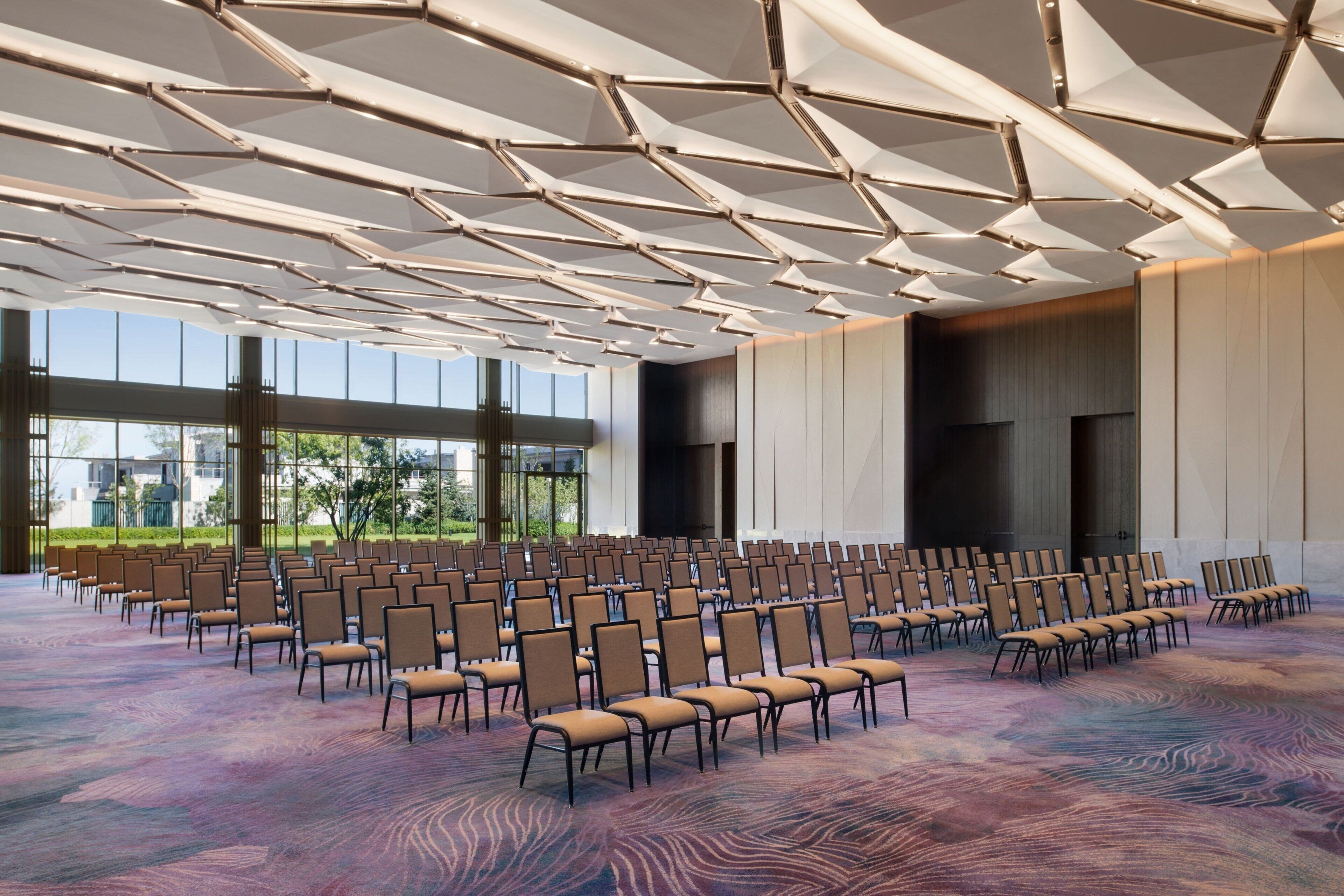 A large conference room with rows of chairs, a patterned carpet, and a modern ceiling design.