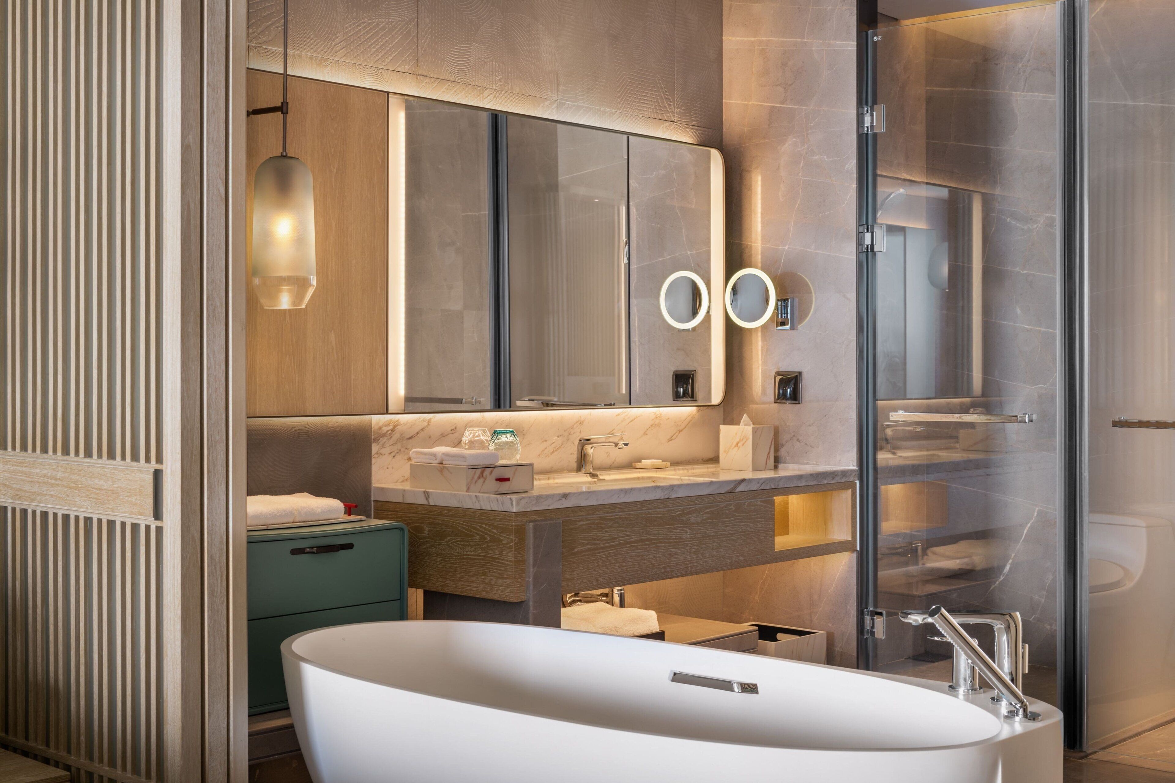 Ein modernes Badezimmer mit freistehender Badewanne, einer Duschkabine aus Glas und einem Waschtisch mit Spiegel.