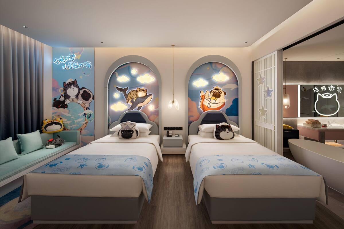 A hotel room with two beds, a sofa, and a desk.