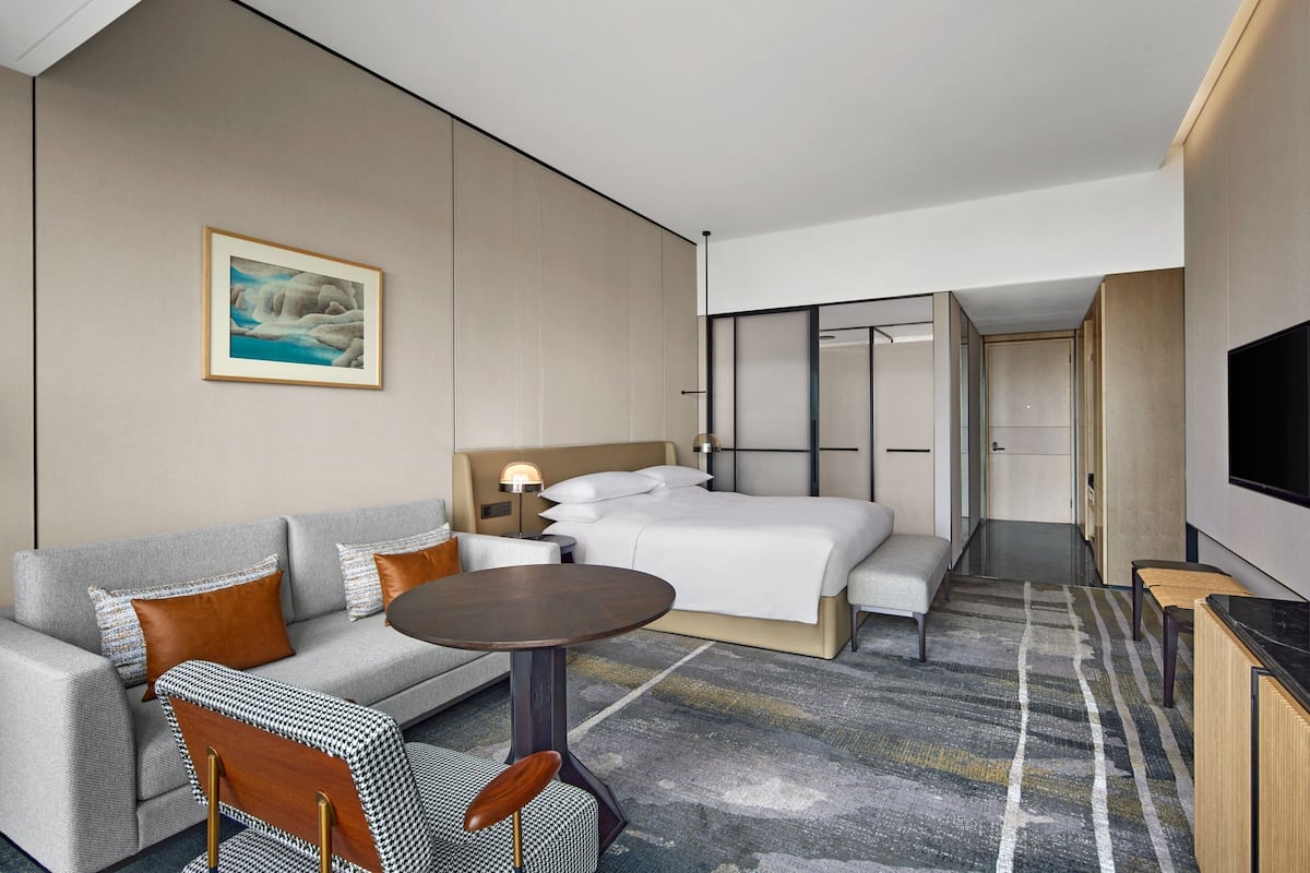 Ein modernes Hotelzimmer mit einer Couch, einem Bett, einem kleinen Tisch und einem Fernseher.