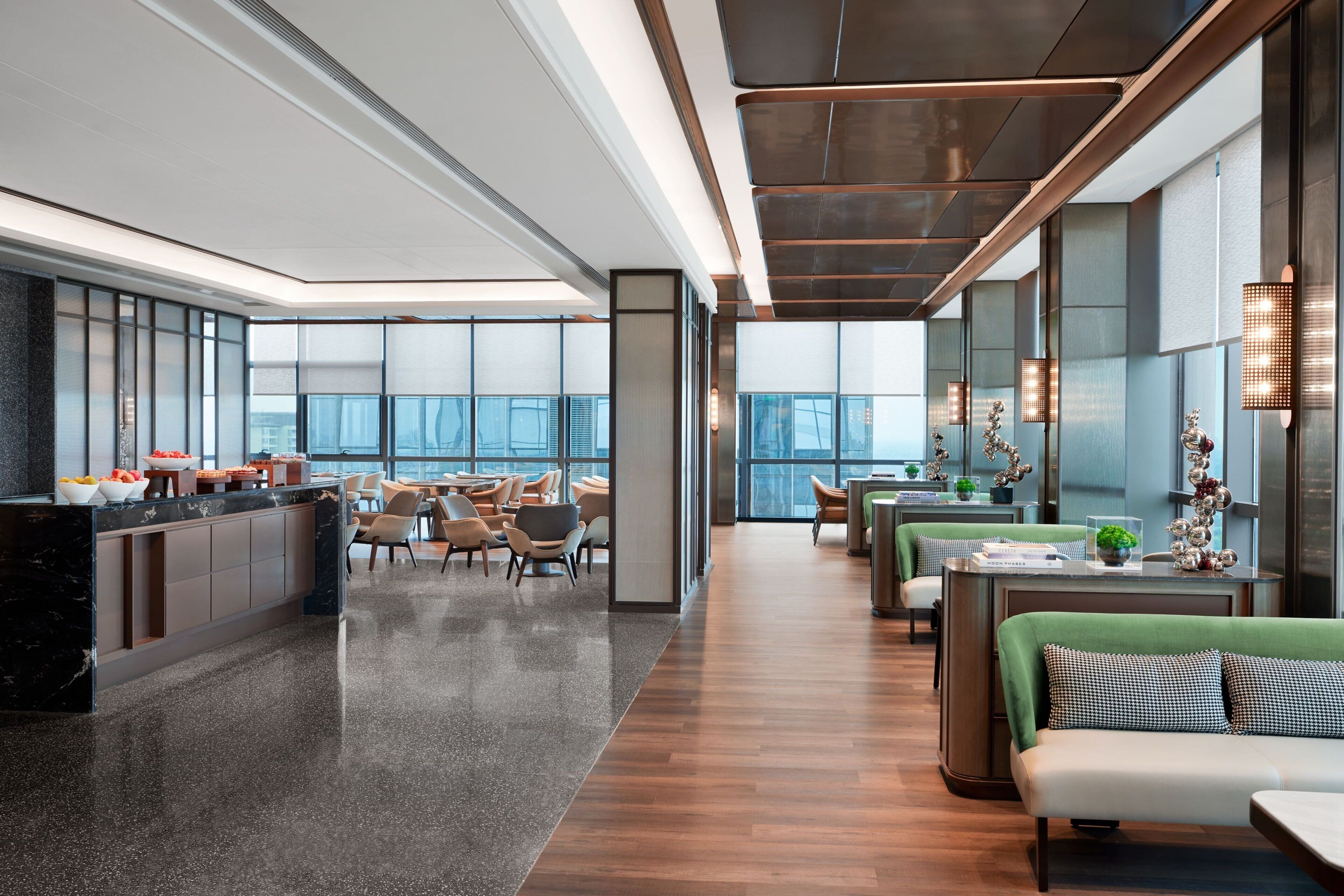 Een moderne hotellobby met een receptiebalie, een zithoek en grote ramen met uitzicht op de stad.