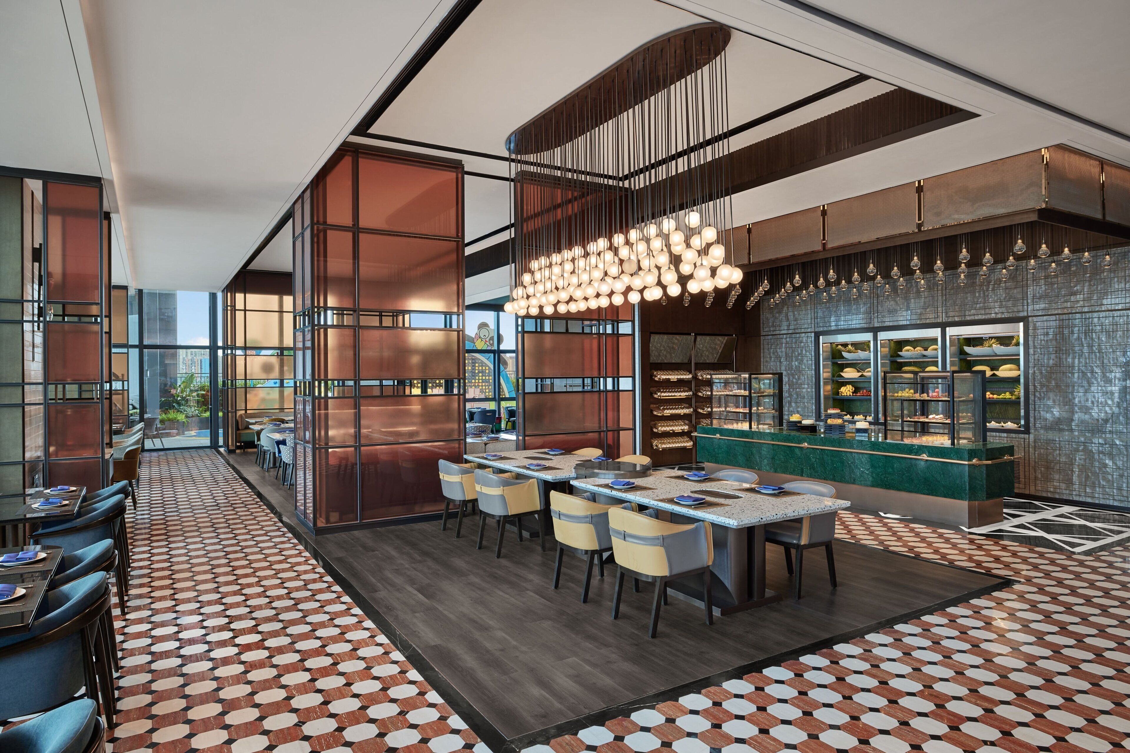 A modern restaurant with a long counter, multiple seating areas, and a decorative light fixture.