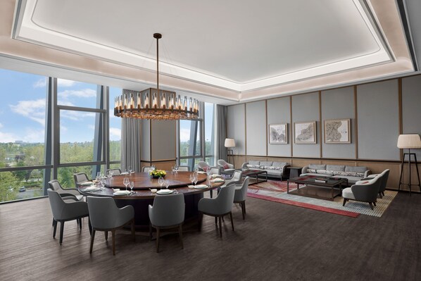 Una habitación amplia con una gran mesa de comedor, asientos cómodos, un sofá y vistas al exterior.