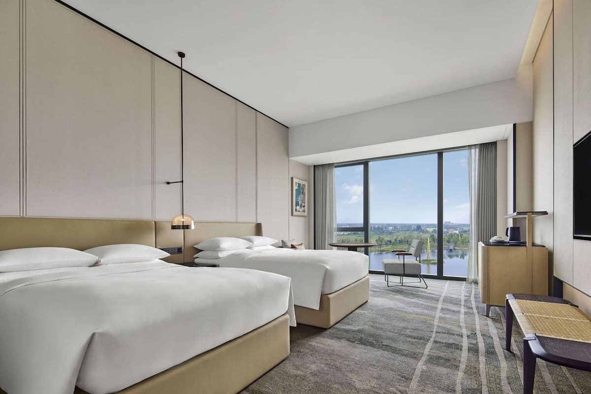 Ein Hotelzimmer mit zwei Betten, einem großen Fenster mit Blick, einem Flachbildfernseher und einem kleinen Tisch.