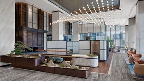 Eine moderne Lobby mit Sitzgelegenheit, einer Rezeption und einem großen Fenster mit Blick auf die Stadt.