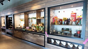 A kitchen with wooden cabinets, a countertop with various items, and a display of cereal boxes.