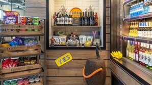 A store interior with shelves stocked with snacks, beverages, and a sign indicating a beer section.
