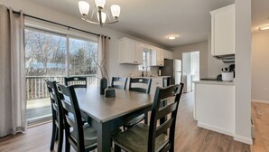 A modern kitchen with white cabinets, a dining table with chairs, and a chandelier. - Pondside View Family Friendly Home!  [Moose Lodge] (Bar Harbor)