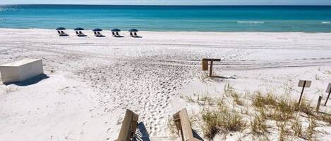 Une plage avec une promenade en bois menant à des parasols de plage.