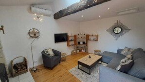 A modern living room with a grey sofa, a coffee table, a TV, and a bookshelf.