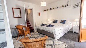 A bedroom with a bed, two bedside tables, a chair, a radiator, a mirror, and a staircase.