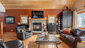A cozy living room with a fireplace, leather sofas, and a stone coffee table. - 3 Bears Cabin | Games Room | Firepit | Lux Kitchen (Invermere)