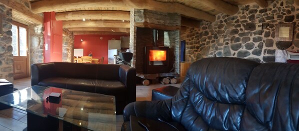 A cozy living room with a stone wall, a fireplace, leather sofas, and a glass coffee table.