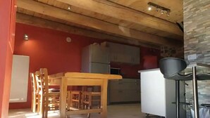 Une cuisine avec des meubles de rangement en bois, un réfrigérateur blanc et un tabouret de bar.