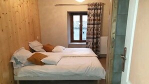 Une petite pièce avec un lit, une fenêtre et une porte.