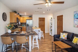 Una cocina moderna con armarios de madera, una isla central y un comedor con sillas y una mesa.
