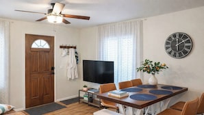 A dining area with a wooden table, chairs, a television, and a clock on the wall. - Cozy Coastal Home, 2 Mi to Navarre Beach (Navarre)