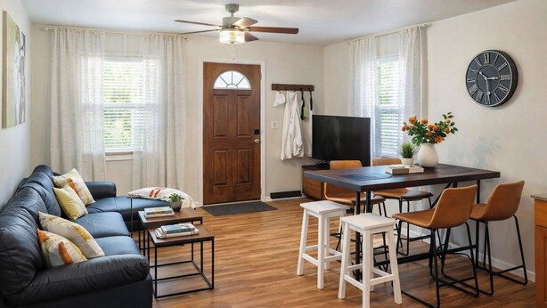 A living room with a sofa, coffee table, TV, dining table with chairs, and a clock on the wall. - Cozy Coastal Home, 2 Mi to Navarre Beach (Navarre)