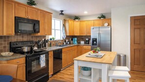 A modern kitchen with wooden cabinets, a stainless steel refrigerator, a microwave, a stove, and a sink. - Cozy Coastal Home, 2 Mi to Navarre Beach (Navarre)