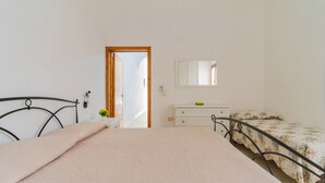 A bedroom with two beds, a dresser, a mirror, and a door leading to another room.