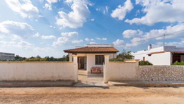 Un immobile residenziale con patio, un piccolo tavolo e una porta d'ingresso.