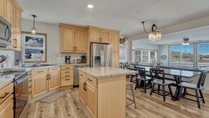 A spacious kitchen with wooden cabinets, stainless steel appliances, and a central island with bar stools.