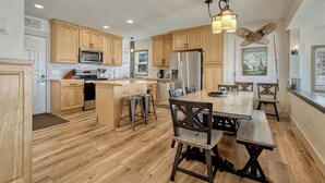 A spacious kitchen with wooden cabinets, a stainless steel refrigerator, and a dining area with a large wooden table and chairs.